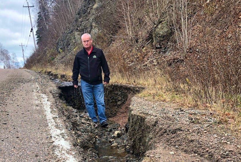 Larry Dauphinee, deputy warden with Victoria County, stands in an eroded portion of the Cabot Trail just south of Ski Cape Smokey in the aftermath of last Tuesday's massive rainstorm. CONTRIBUTED