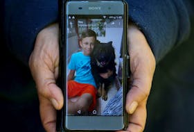 A closeup shows a phone-size photo of one of Christina Kennis' two beloved dogs, Chloe, with her 15-year-old son, Lucas.