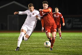 George Takacs (left) of the UNB Reds and Memorial Sea-Hawks captain Harry Carter (4) chase down the ball in AUS men's soccer quarter-final play in Sydney, N.S., Thursday night. Tkacs had the game's only goal in a 1-0 UNB victory. — Cape Breton University Athletics photo/Vaughan Merchant