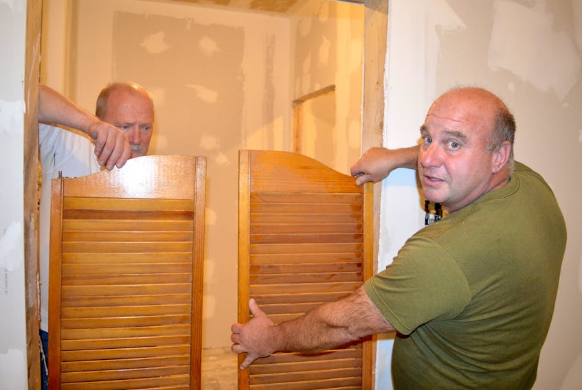 Paul Prince, left, and George Della Valle prepare to install doors leading into the bathroom at the Royal Canadian Legion in Dominion. Money from the annual poppy campaign supports a number of programs that help veterans and their families, including Operation VetBuild. Although it began as a weekly model-building group, the Dominion branch members soon decided instead to completely remodel the building’s basement. Chris Connors/Cape Breton Post

