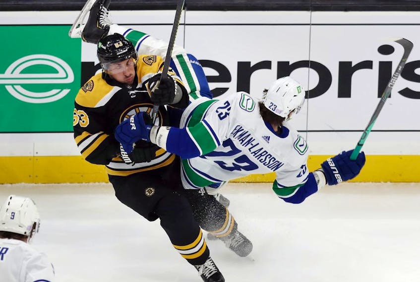 Bruins' Brad Marchand, left, checks Vancouver Canucks' Oliver Ekman-Larsson during the first period of NHL play on Nov. 28 in Boston.