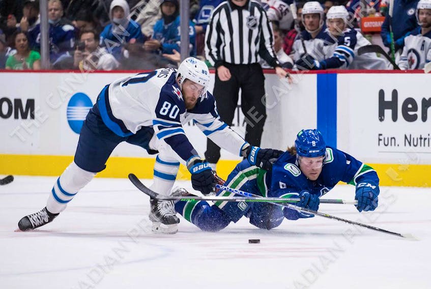  Canucks forward Brock Boeser dives to swat the puck away from Winnipeg Jets’ Pierre-Luc Dubois during the first period at Rogers Arena in Vancouver on Friday, Dec. 10, 2021.