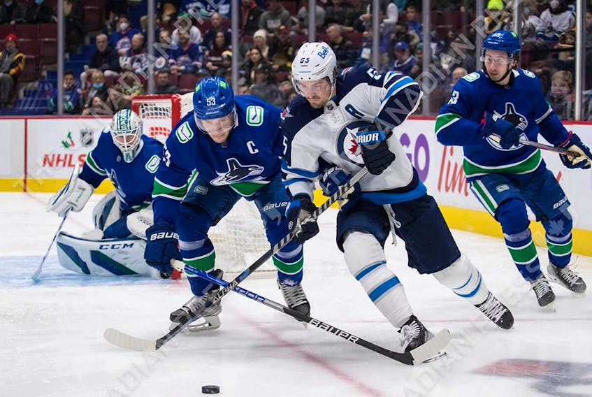  Canucks’ Bo Horvat checks Winnipeg Jets’ Mark Scheifele during the first period of play at Rogers Arena in Vancouver on Friday, Dec. 10.
