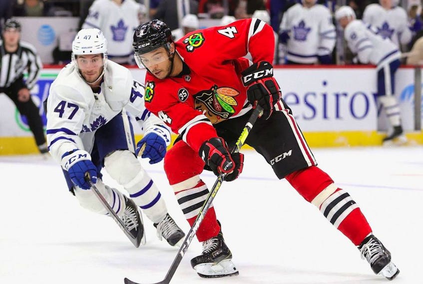 Seth Jones, right, of the Blackhawks advances the puck past Maple Leafs forward Pierre Engvall during NHL action at the United Center in Chicago, Oct. 27, 2021.