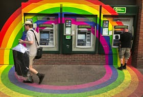 A customer withdraws money from an ATM at a Toronto-Dominion (TD) bank branch adorned in colours of the Pride rainbow flag symbolizing gay rights, in downtown Toronto in 2017. Recently, the House of Commons voted unanimously to ban LGBT conversion therapy, which seeks to change a person's sexual orientation or gender identity and has been condemned by medical professionals. - REUTERS/Chris Helgren