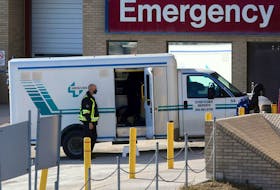 A health care worker helps unload a stretcher service vehicle at St. Boniface Hospital in Winnipeg on Nov. 1, 2020. 