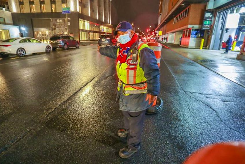 Parking attendant Sam Suos waves cars past the Bell Centre parking lot ahead of the Montreal Canadiens' game against the Philadelphia Flyers in Montreal on Thursday, Dec. 16, 2021 after the Canadiens were asked by Quebec's public health department to hold the game without fans. 