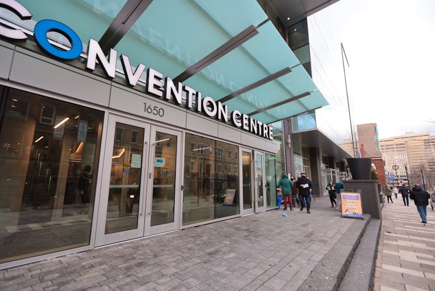 People line up outside the Halifax Convention Centre in two lines: to receive a box of rapid test kits, of receive the test kits and go inside to have a PRC test.