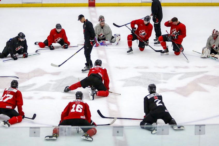 Players stretch as head coach Dave Cameron, centre left, gives instruction during a practice at the Canadian World Junior Hockey Championships selection camp in Calgary, Thursday, Dec. 9, 2021.