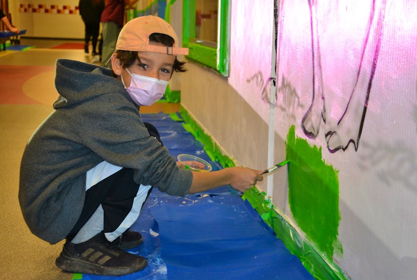 Bronson Stevens paints grass as part of a mural honouring the Seven Sacred Teachings. The Grade 5 student is participating in the first art therapy program at Maupeltuewey Kina'matno'kuom and said, "I think we're doing a good job." ARDELLE REYNOLDS/CAPE BRETON POST