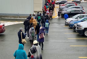 The long line stretched outside the Shoppers Drug Mart on Lemarchant Road in St. Johns Monday morning, Dec. 20, a people waited to receive a COVID-19 vaccine booster shot.