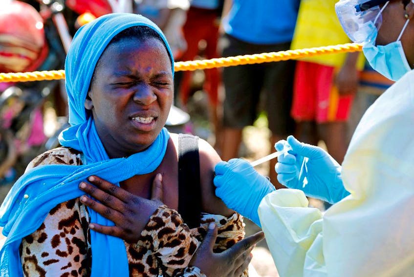 A young woman reacts as a health worker injects her with the Ebola vaccine, in Goma, Democratic Republic of Congo, in 2019.