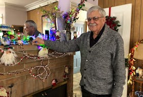 Lloyd Tattrie stands by a fireplace mantle in the home where generations of his family have celebrated Christmas. 
