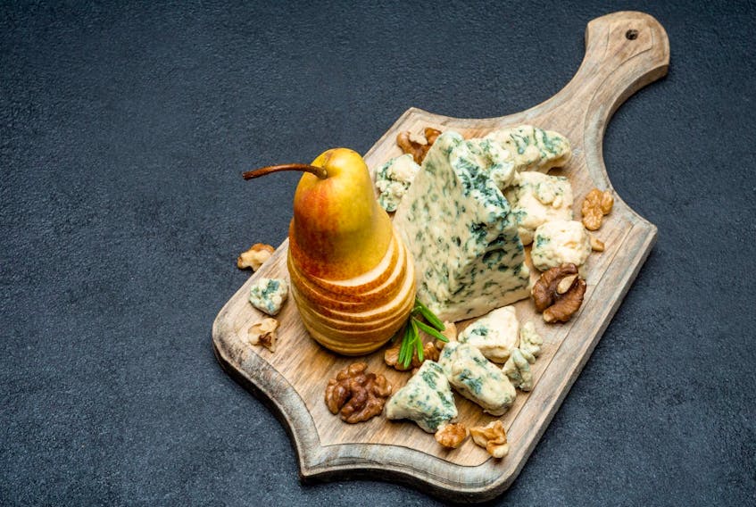 Slice of French Roquefort cheese and figs on wooden cutting board