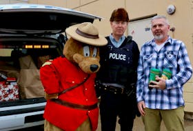Peter Armstrong picked up some extra peanut butter when he went grocery shopping at Sobeys and donated it during the Stuff a Cruiser fundraiser Dec. 11. Pictured with him are RCMP Const. Ian Murphy and Safety Bear.