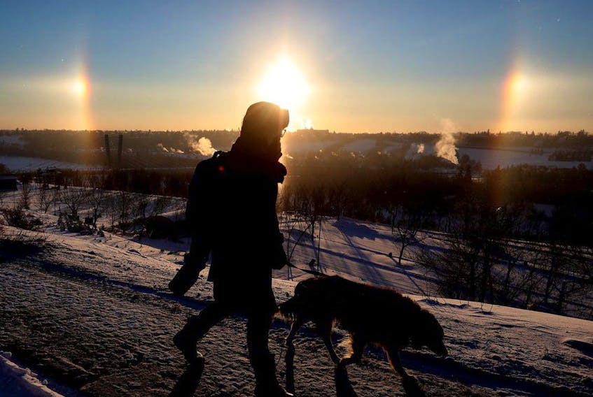 A pedestrian walks past a sundog hanging over Edmonton's river valley, Friday Dec. 17, 2021. 