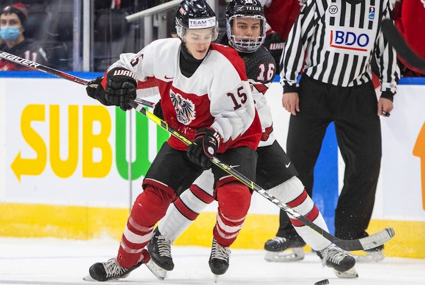 Canada's Connor Bedard, right, and Austria's Fin van Ee battle for the puck during Tuesday night's world junior hockey championship game in Edmonton. Bedard had four goals to lead Canada to an 11-2 win.