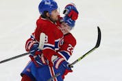 Montreal Canadiens' Cole Caufield (22) celebrates the goal of teammate Ben Chiarot (8) during second period in Montreal on Thursday, Dec. 2, 2021. 