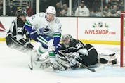  Vancouver Canucks’ Quinn Hughes, centre, goes after the puck deflected by Los Angeles Kings goaltender Jonathan Quick during first period of an NHL hockey game Thursday, Dec. 30, 2021, in Los Angeles.
