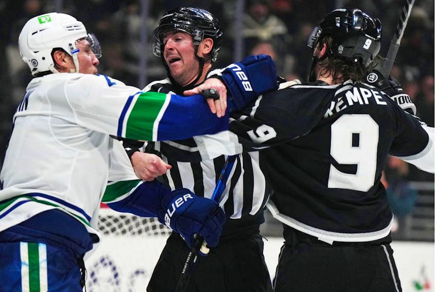  NFL referee Tom Chmielewski (centre) attempts to break up a fight between Vancouver Canucks defenceman Luke Schenn (2) and LA Kings centre Adrian Kempe (9) in the second period at Crypto.com Arena.
