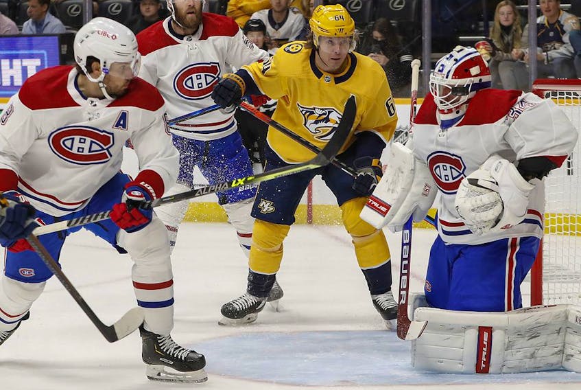 Predators' Mikael Granlund (64) watches as Canadiens goalie Jake Allen blocks a shot with his mask during the first period at Bridgestone Arena on Saturday, Dec. 4, 2021, in Nashville.