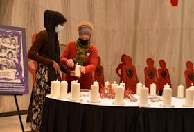 Zamzam Aden, left, and Yvette Doucette, who are with the Immigrant and Refugee Services Association P.E.I., light a candle for peace at the Montreal Massacre memorial service, held Dec. 6 in Charlottetown at Confederation Centre of the Arts' Memorial Hall.