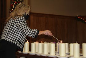 At Summerside's National Day of Remembrance and Action on Violence Against Women service on Monday, Dec. 6, a woman lights a candle in memory of the victims of the 1989 École Polytechnique shooting.