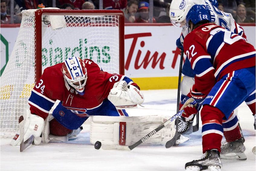 Montreal Canadiens goaltender Jake Allen prepares to cover the puck as right-winger Cole Caufield keeps Tampa Bay Lightning left-winger Ross Colton at bay during second period in Montreal on Dec. 7, 2021.