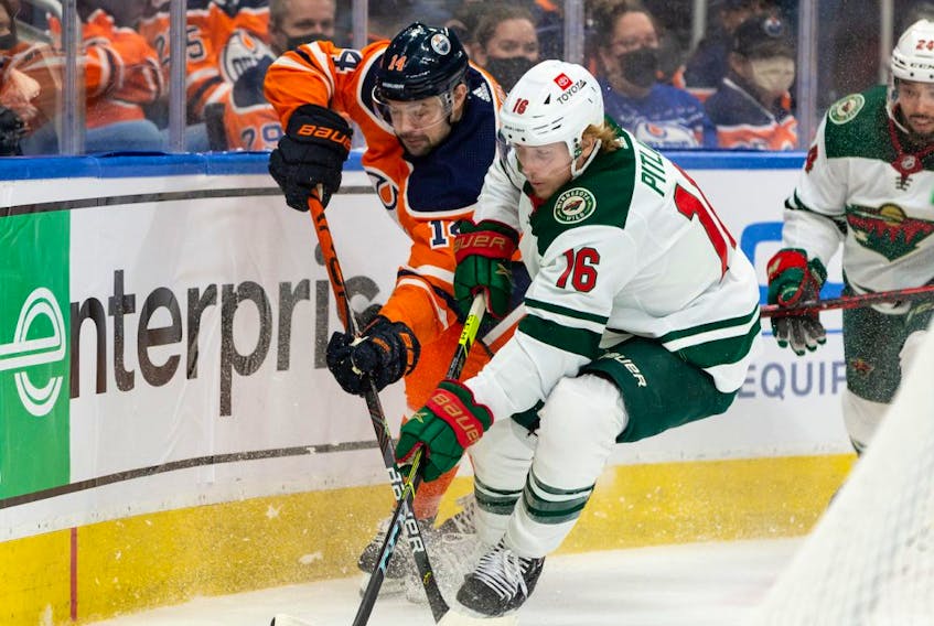 Edmonton Oilers’ Devin Shore (14) battles Minnesota Wild’s Rem Pitlick (16) during third period NHL action at Rogers Place in Edmonton, on Tuesday, Dec. 7, 2021. 