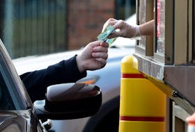 A fast-food restaurant employee accepts payment for an order at a local franchise in St. John’s.