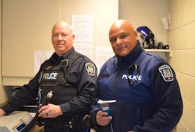 Const. Dale Johnson, left, displays a device used to screen a person's blood alcohol level on Dec. 9 at Charlottetown Police Services, while Const. Tim Keizer holds an approved screen device for roadside impaired driving.