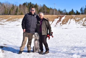 Scott Hagell, left, and Ginny Hingley with their furry friend, Addison, on the field. Hingley has spearheaded efforts to develop the area as a green space.