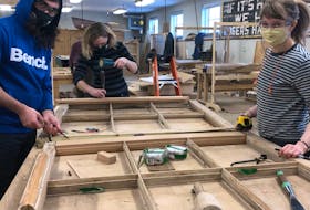 Heritage retrofit carpentry students, from left, Adran Shojaei, Charlotte Morrison and Megan Stewart, work on one of the windows from Province House. 