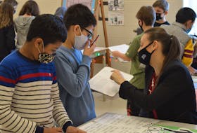 Grade 5 teacher Samantha Ralph crunches the numbers with Nick Do as fellow student Shuvomoy Burma looks on during a financial fair recently at West Royalty Elementary School in Charlottetown.