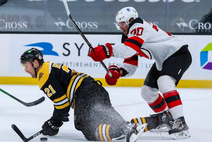 New Jersey Devils defenseman Dmitry Kulikov (70) checks Boston Bruins left wing Nick Ritchie (21) during the first period at TD Garden on March 30, 2021. 