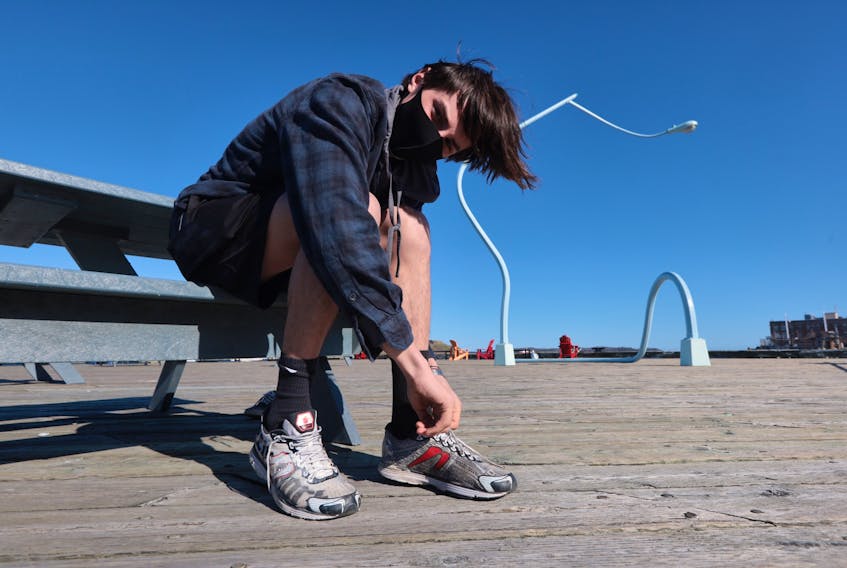 April 12, 2021 - Adrian Delli Colli laces up his running shoes along the Halifax boardwalk Monday afternoon. Delli Colli is helping organize Sunday's Nova Scotia Remembers Memorial Road Race to honour the memories and families of the victims of the mass shooting, which happened one year ago on April 18 and 19.