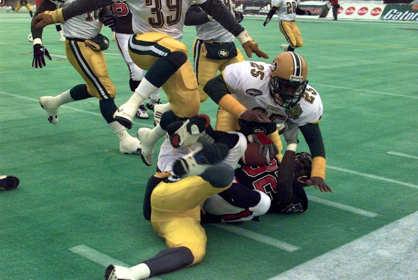Edmonton Football Team defensive back Don Wilson (25) hits the pile to bring down Calgary Stampeders ball carrier Kelvin Anderson (32) in the West Division final on Nov. 14, 1998.