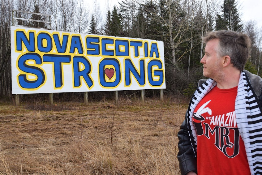 North River resident and professional magician David Johnston stands before the Nova Scotia Strong billboard that he and some other community members created over two days as a show of support for the families of last week's 22 shooting victims. The dilapidated billboard had stood in a plain state for 25 years. - Harry Sullivan