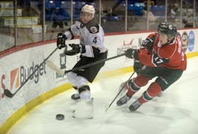 Charlottetown Islanders rookie Ryan Maynard, left, flips the puck behind the Halifax Mooseheads net while being defended by defenceman Cam Whynot Tuesday at the Eastlink Centre in Charlottetown.