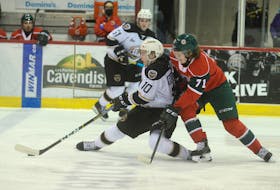 Charlottetown Islanders captain Brett Budgell, left, tries to get the puck to a teammate while fending off the check of Halifax Mooseheads centre Attilio Biasca Tuesday at the Eastlink Centre in Charlottetown.