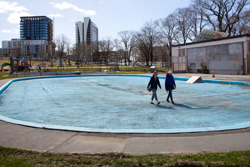 Two people walk across the drained wading pool, at the dated Halifax Commons swimming facility Thursday, April 8, 2021.