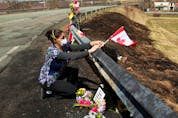  Care worker and first responder Alicia Cunningham adjusts a Canadian flagat a makeshift memorial for slain RCMP Const. Heidi Stevenson.