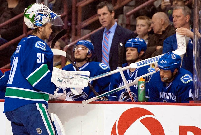 Goalie Eddie Lack gets a stick from equipment manager Pat O'Neill while relieving Roberto Luongo during a game against the Winnipeg Jets on Dec. 22, 2013.