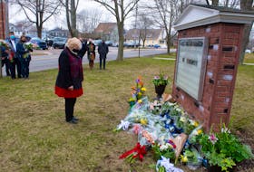 Christine Blair, mayor of the Municipality of Colchester, takes a moment to reflect after placing flowers outside First United Church in Truro on Sunday. The church hosted a memorial service for family members of the victims of last year's mass shooting.