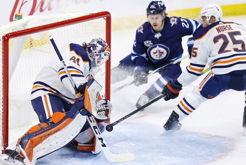 Winnipeg Jets center Mason Appleton (22) and Edmonton Oilers defenseman Darnell Nurse (25) watch as Edmonton Oilers goaltender Mike Smith (41) blocks a shot in the first period at Bell MTS Place on April 17, 2021. 