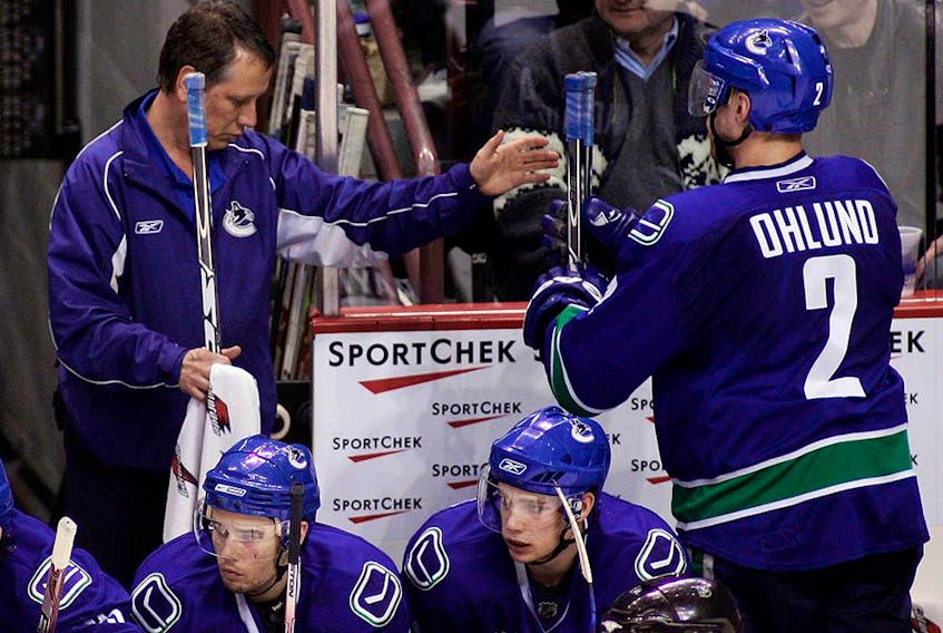 Canucks equipment manager Pat O'Neill (left) hands Mattias Ohlund a stick during a game in October 2008.