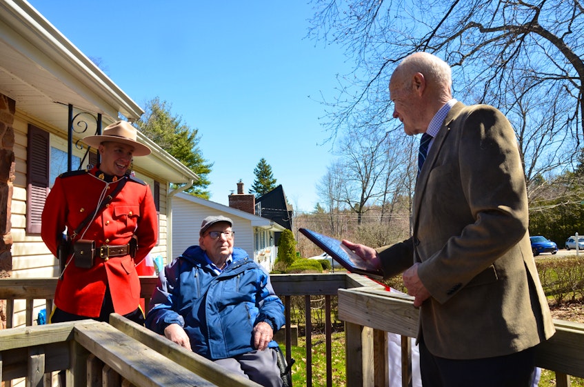As RCMP Const. Remy Gauvin, left, looks on, Kings County Mayor Peter Muttart, right, presents a municipal plaque to Hormidas Fredette of New Minas, who turned 104 years old on April 11. KIRK STARRATT