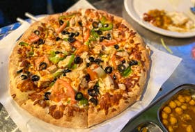 The Butter Chicken Pizza comes with olives, tomatoes and green peppers. 