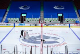 An arena worker removes the net from the ice after the Vancouver Canucks and Calgary Flames NHL hockey game was postponed due to a positive COVID-19 test result, in Vancouver, on Wednesday, March 31, 2021.