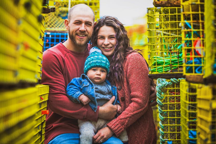 Millen Boyd and Fallon Conway with their son Loki amongst their lobster traps two weeks ago. Boyd and his crew were saved Wednesday off Whitehead when his boat capsized. Photo by Kennedy Fraser.